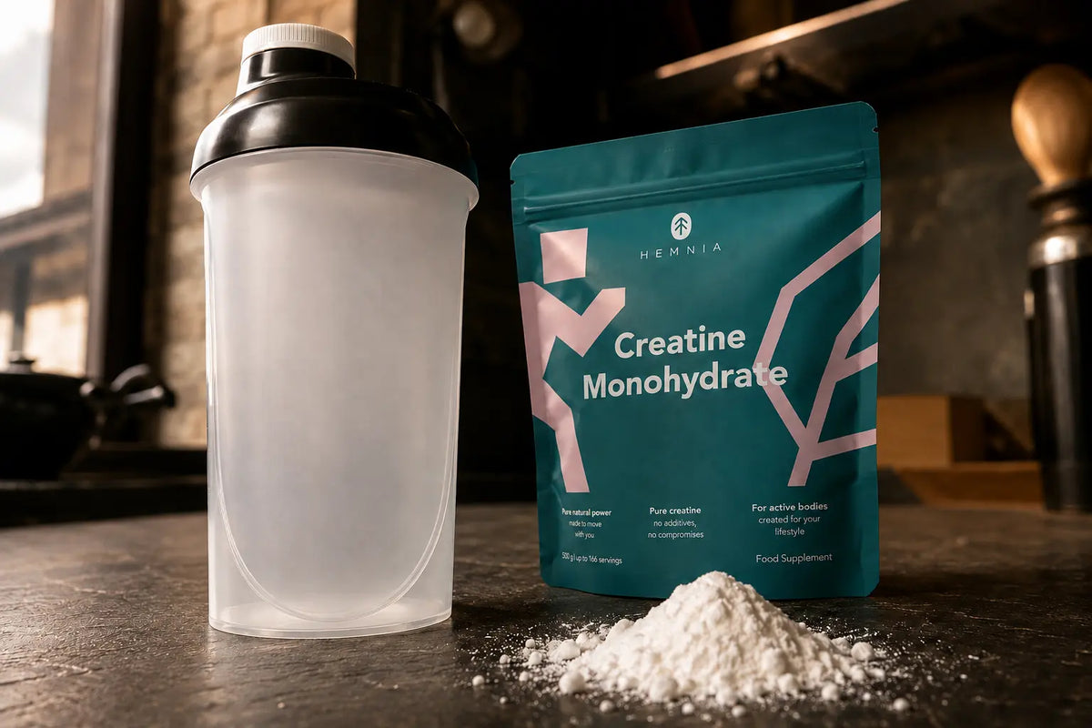 A shaker bottle and Hemnia creatine monohydrate powder on a table.